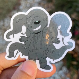 A sticker of a black skeleton that is dripping and has four tentacles coming from his back.