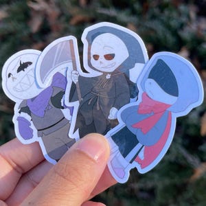 Three skeletons. The one on the left is pushing his chest out, the one in the middle is a grim reaper, and the one on the right has his hood covering his eyes.