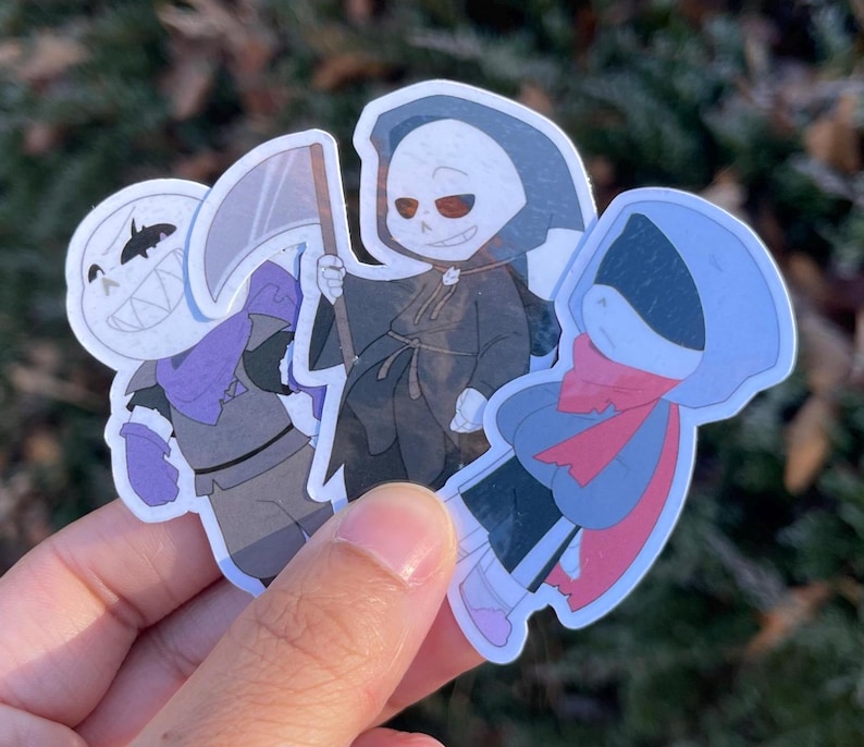 Three skeletons. The one on the left is pushing his chest out, the one in the middle is a grim reaper, and the one on the right has his hood covering his eyes.