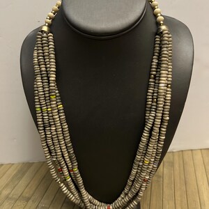 May include: A multi-strand necklace made of light brown wooden beads with accents of red, yellow, and blue beads.