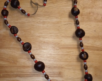 May include: A necklace made of brown buckeyes and red and gray beads.