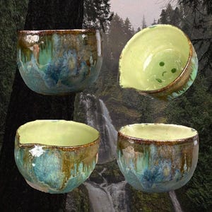 May include: A set of four ceramic bowls featuring a reactive glaze with swirling shades of blue, green, and brown. The bowls have a rounded shape with a small pouring spout on the rim and a smooth, light green interior finish with small dots.