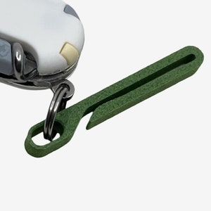 Könnte beinhalten: Ein grüner Schlüsselanhänger aus Kunststoff mit einem Flaschenöffner, der an einem silbernen Ring befestigt ist.