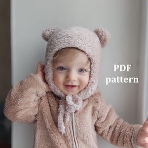 May include: A baby wearing a light brown fuzzy jacket and a light brown fuzzy bear hat with ear flaps. The text "PDF pattern" is written in white on a white background.
