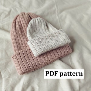 以下が含まれることがあります： ピンクとクリーム色のニット帽が2つ重ねられています。帽子はリブ編みでシンプルなデザインです。画像の下部に「PDF pattern」というテキストが表示されています。