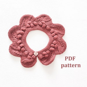 Könnte beinhalten: Ein gestrickter Kragen mit gewelltem Rand und einem herzförmigen Knopf. Der Kragen ist dunkelbordeauxfarben und hat ein strukturiertes Muster. Das PDF-Muster ist enthalten.