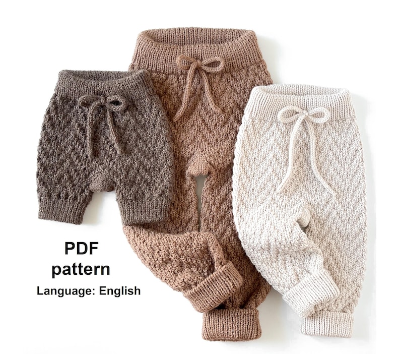 May include: Three pairs of knitted baby trousers in brown, beige and white. The trousers have a diamond pattern and a drawstring.
