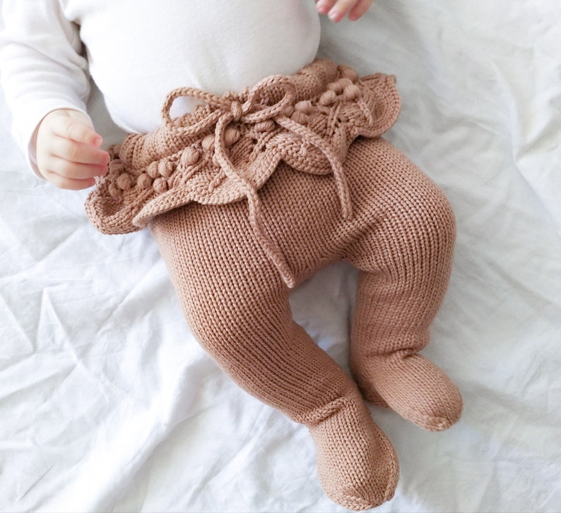 Op de afbeelding: Bruine gebreide baby leggings met een geruite zoom en pompoenen rond de taille.
