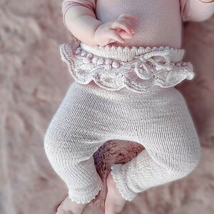 Op de afbeelding: Een gebreide baby leggings met een geruite tailleband en een strikdetail. De leggings zijn lichtroze.