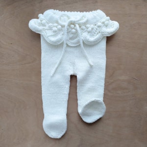 Op de afbeelding: Witte gebreide baby leggings met een witte gehaakte ruche rond de taille.