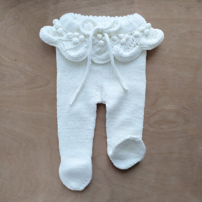 Op de afbeelding: Witte gebreide baby leggings met een witte gehaakte ruche rond de taille.