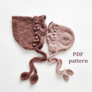 May include: Two knitted baby bonnets with pom-poms, one in a deep brown and one in a light pink, with long ties. PDF pattern.