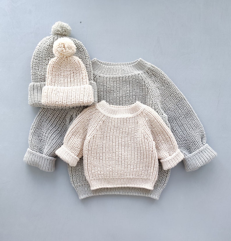 Puede incluir: Dos jers&eacute;is de punto, uno gris y otro crema, con un gorro de punto crema con un pomp&oacute;n blanco.