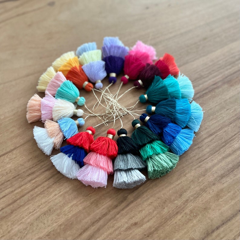 Pode incluir: Uma cole&ccedil;&atilde;o de 20 brincos de franja coloridos em v&aacute;rios tons de azul, verde, vermelho, rosa, roxo, laranja e amarelo. As franjas s&atilde;o de duas camadas e t&ecirc;m detalhes dourados.