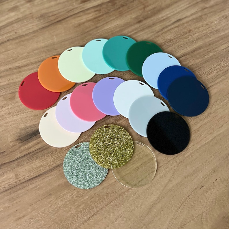 May include: A collection of circular acrylic blanks in various solid colours including red, orange, light green, mint, teal, dark green, light blue, navy, pink, lavender, white, cream, and black, plus gold glitter, silver glitter, and clear discs.