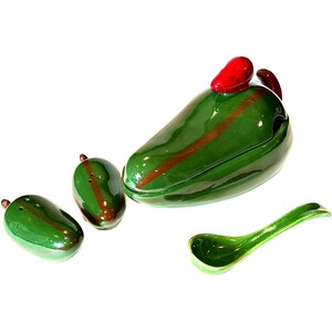 May include: A ceramic green chili pepper-shaped serving set. The set includes a large lidded dish, two salt and pepper shakers, and a spoon. The chili pepper has a red stem and a brown stripe down the middle.