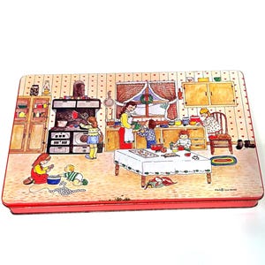 May include: Rectangular tin with a painted kitchen scene. The illustration depicts a family baking, with a woman and children around a table and stove. The tin has a red border and a white background with a heart pattern.