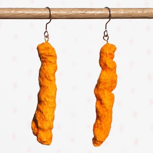 May include: A pair of orange, textured, fried food shaped earrings hanging from silver hooks.