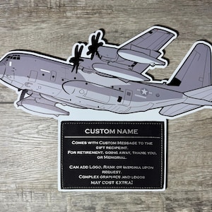 May include: A gray and white paper cutout of a C-130 Hercules airplane with a black rectangle at the bottom that says "CUSTOM NAME" and includes text about adding a custom message and logo.