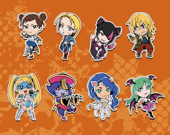 May include: Eight cartoon character pins featuring characters from the Street Fighter video game series. The characters are Chun-Li, Ryu,  Sakura, Guile,  Ken,  Blanka,  Cammy, and  Morrigan. The pins are colorful and feature the characters in their signature poses.