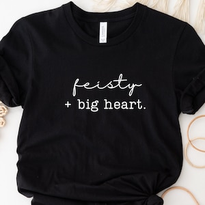 May include: Black t-shirt with white text that reads "feisty + big heart."