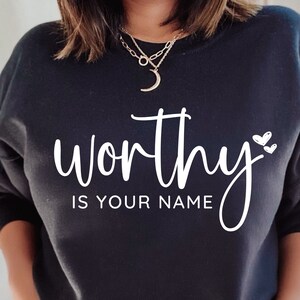 May include: Black sweatshirt with the text "worthy is your name" in white lettering with two small white hearts.