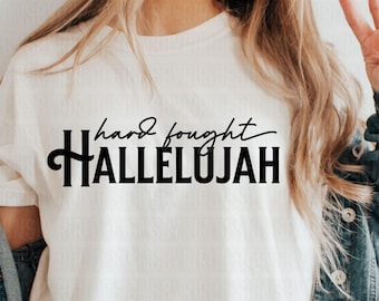 May include: White t-shirt with black text that reads "hard fought HALLELUJAH"