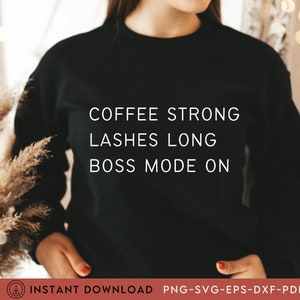 Op de afbeelding: Een zwart sweatshirt met witte tekst die "Coffee Strong Lashes Long Boss Mode On" zegt.