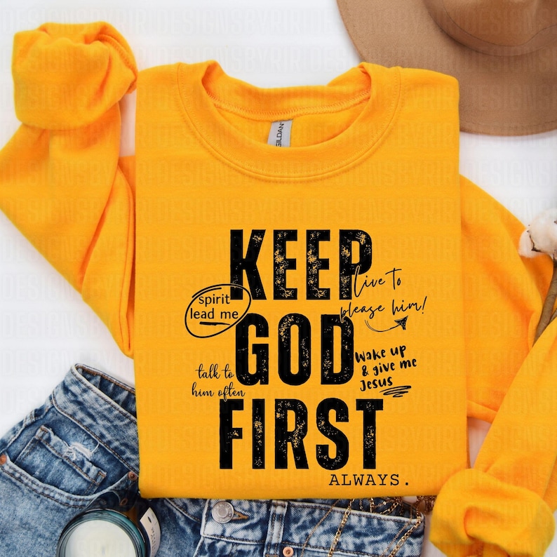 May include: A yellow sweatshirt with the text "KEEP GOD FIRST ALWAYS." in black. The text is in a distressed font and includes additional text in smaller font around the main text, such as "spirit lead me", "talk to him often", "live to please him!" and "wake up & give me Jesus".