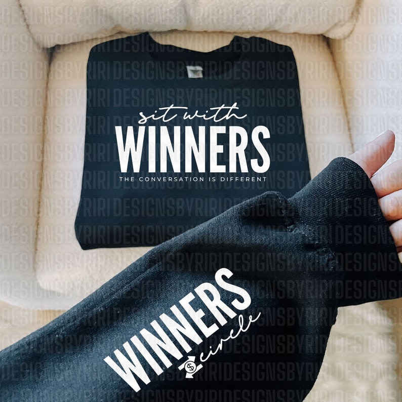 May include: Black t-shirt with white text that reads "Sit with Winners. The conversation is different."  Another black t-shirt with white text that reads "Winners circle" is partially visible.