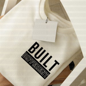 May include: A white sweatshirt with the text "BUILT DIFFERENT" printed in black on the front.