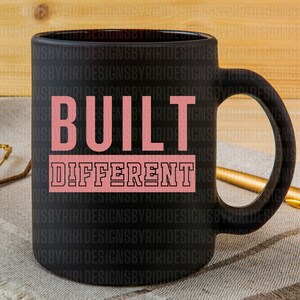May include: Black coffee mug with a pink and black design that says "BUILT DIFFERENT".