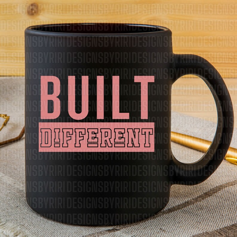 May include: Black coffee mug with a pink and black design that says "BUILT DIFFERENT".