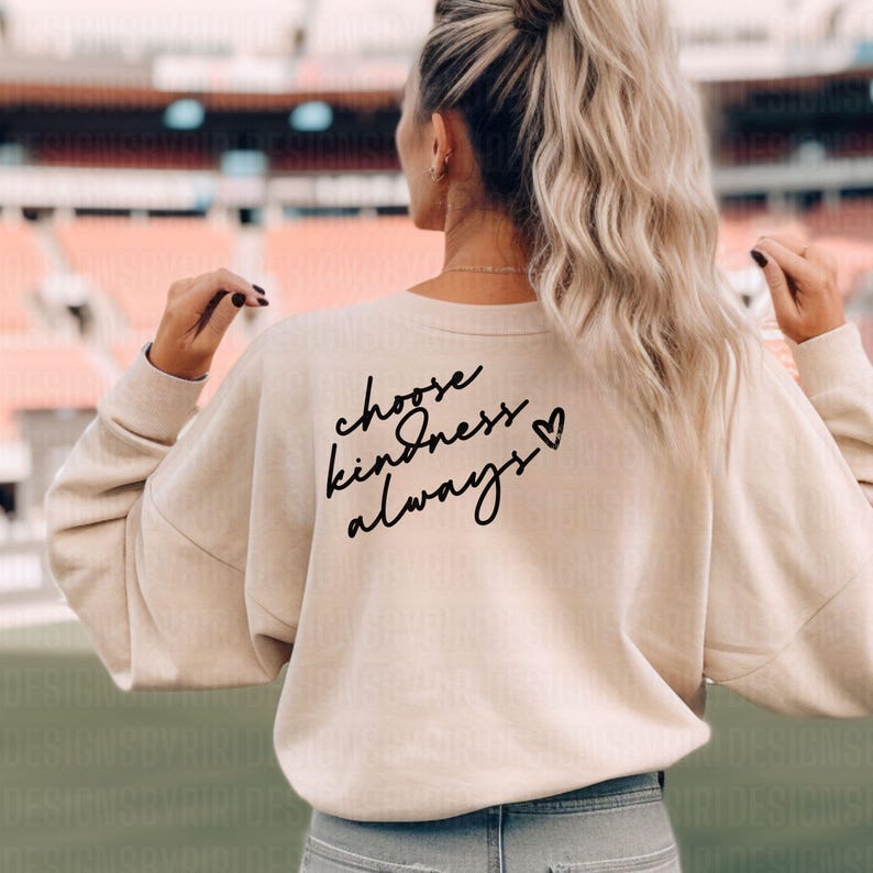 以下が含まれることがあります： 背面に「choose kindness always」というテキストと小さなハートのシンボルがプリントされたベージュのスウェットシャツです。
