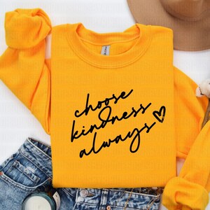 以下が含まれることがあります： 「choose kindness always」という黒い文字と小さなハートマークが書かれた黄色のスウェットシャツです。