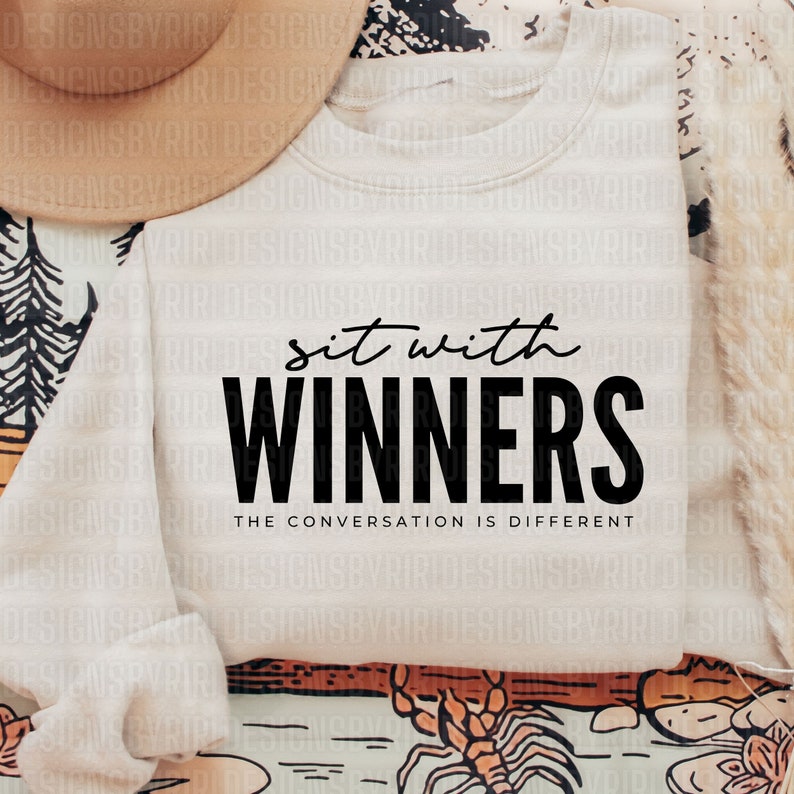 May include: A white sweatshirt with the text "sit with WINNERS THE CONVERSATION IS DIFFERENT" printed in black.