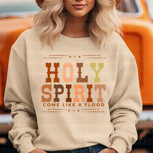 May include: A beige sweatshirt with a brown, orange, and yellow graphic that says "HOLY SPIRIT COME LIKE A FLOOD".