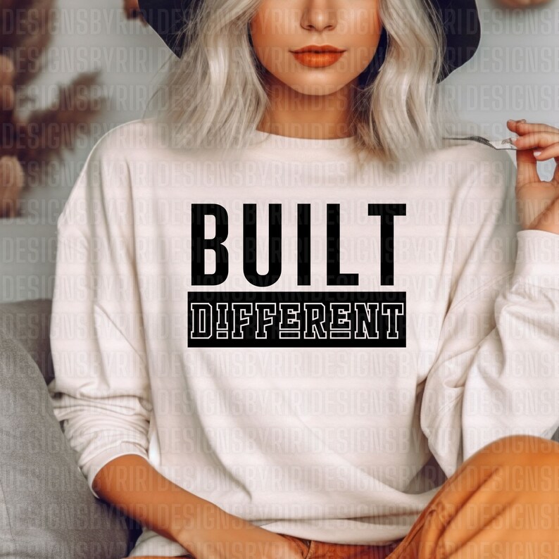 May include: A white long-sleeved sweatshirt with the text "BUILT DIFFERENT" printed in black on the front.