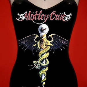 以下が含まれることがあります： 黒いタンクトップ。バンド名「Mötley Crüe」が赤と白のスクリプトで書かれています。シャツには、翼のある杖に巻き付いたヘビのグラフィックと、赤い文字で「Dr. Feelgood」と書かれています。