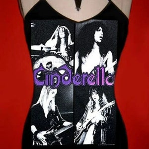 May include: Black halter top with a four-panel image of the band Cinderella and their name in purple script. A black necklace with a coffin pendant is also visible.