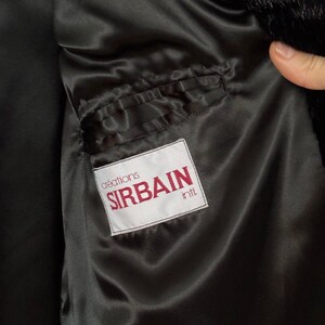 Puede incluir: Un abrigo de piel negro con forro de sat&eacute;n negro. El forro tiene un bolsillo con una etiqueta blanca que dice "cr&eacute;ations SIRBAIN int'l".