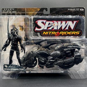 May include: A black Spawn action figure with a motorcycle. The figure is posed on the motorcycle, which has a black and silver paint job. The packaging features the words "Spawn Nitro Riders" and "www.spawn.com".