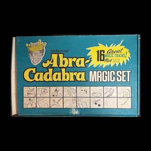 Puede incluir: Caja vintage "Abra-Cadabra Magic Set". La caja es de color turquesa con texto amarillo y blanco. El texto dice "Adams' Abra-Cadabra MAGIC SET" con una imagen de un mago con una corona. La caja anuncia "16 Great Magic Tricks!"