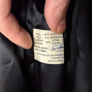 Puede incluir: Una etiqueta de tela blanca con texto negro que detalla la composici&oacute;n de una prenda. La etiqueta dice: "POIL/60% ACRYLIQUE PILE/40% MODACRYL COTON SUPPORT 100% COTTON, GARNITURE G&Eacute;N&Eacute;RALE 100% COTON GENERAL TRIMMING COTTO NETTOYER SELON PROCEDE FURRIER DR MADE IN CANADA"
