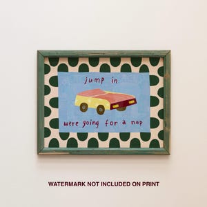 May include: A framed art print featuring a whimsical illustration of a yellow and red car on a light blue background. The text "jump in were going for a nap" is written above and below the car. The frame is green with a polka dot pattern.