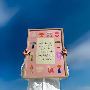 May include: A rectangular framed print with a pink background featuring various colorful lamp illustrations surrounding a central cream-colored rectangle with the text: not to be dramatic but if you put the big light on i'll die. The frame is light wood.