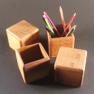 Peut inclure: Quatre boîtes en bois, dont trois sont vides et une contient un assortiment de crayons de couleur et de stylos. Les boîtes sont en bois brun clair et ont une finition naturelle.