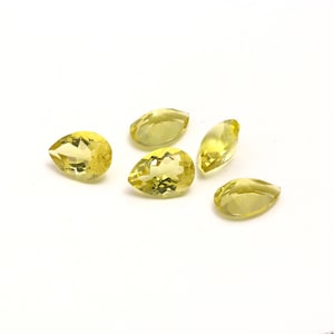 Może przedstawiać: Pięć żółtych kamieni szlachetnych w kształcie gruszki na białym tle.