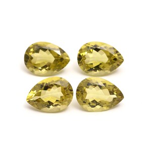 Może przedstawiać: Cztery fasetowane, żółte kamienie szlachetne w kształcie gruszki. Kamienie są półprzezroczyste i mają lekko zielony odcień.