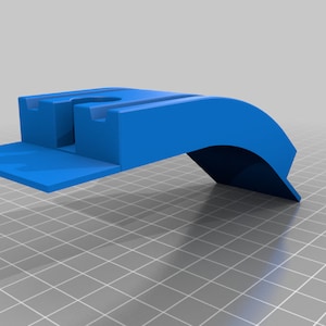 以下が含まれることがあります： 青いプラスチック製の3Dプリントされた携帯電話スタンド。湾曲したアームと折り畳み可能なベースが付いています。スタンドは、携帯電話を垂直に保持するように設計されています。